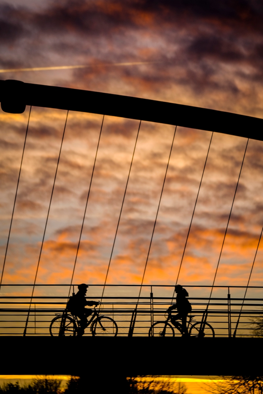 Two cyclists silouetted against the sunset sky while crosing the Millennium Bridge in York, UK.