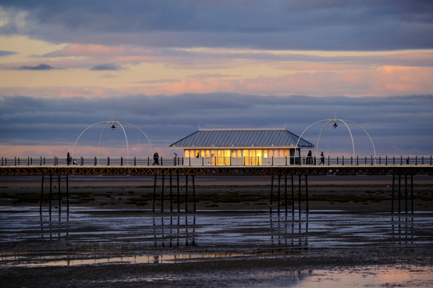 The setting sun reflected in the windows of a shelter on Southport Pier